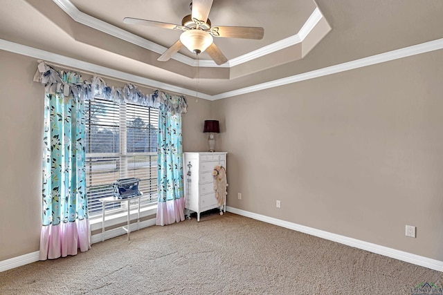 carpeted empty room with baseboards, ceiling fan, a tray ceiling, and crown molding