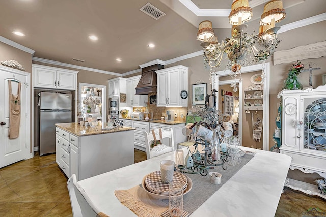 kitchen with a notable chandelier, premium range hood, visible vents, appliances with stainless steel finishes, and a center island