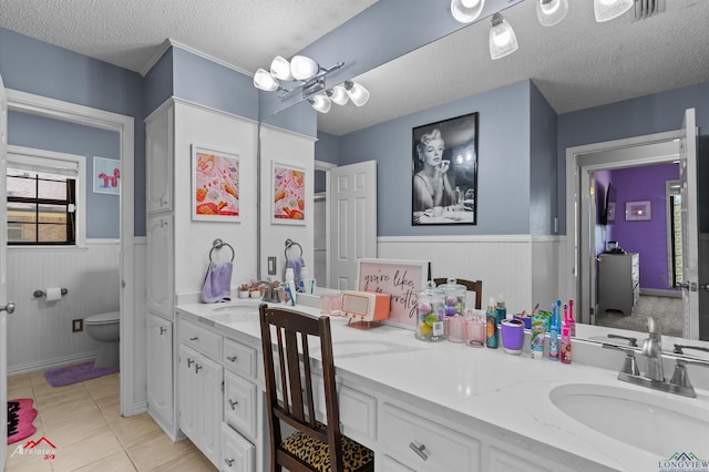 1208 Westwood Dr, Henderson, TX 75654 - full bathroom featuring toilet, a wainscoted wall, a textured ceiling, tile patterned flooring, and vanity