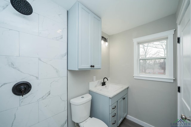 bathroom featuring tiled shower, toilet, and vanity