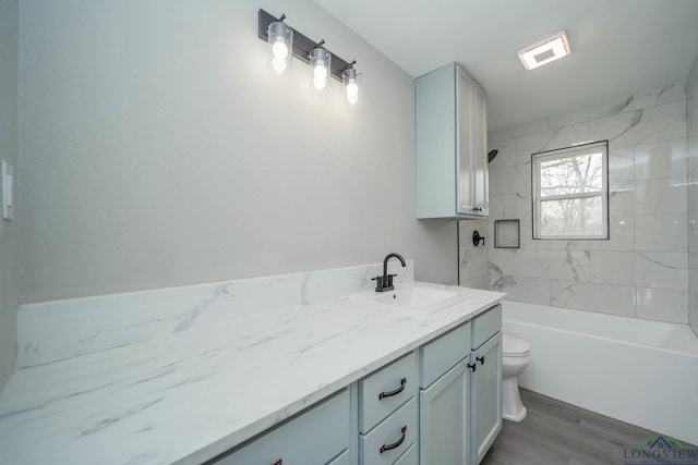 full bathroom with hardwood / wood-style floors, toilet, vanity, and tiled shower / bath combo