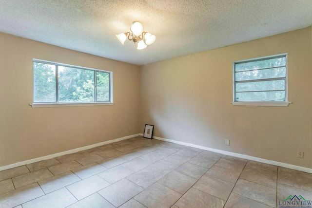 2820 W Upshur Ave, Gladewater, TX 75647 - empty room with a chandelier, tile patterned floors, baseboards, and a textured ceiling