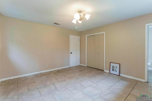 2820 W Upshur Ave, Gladewater, TX 75647 - empty room featuring baseboards, a chandelier, light tile patterned flooring, and a textured ceiling