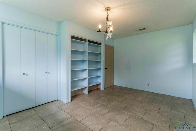 2820 W Upshur Ave, Gladewater, TX 75647 - unfurnished bedroom with a chandelier, a closet, baseboards, and a textured ceiling