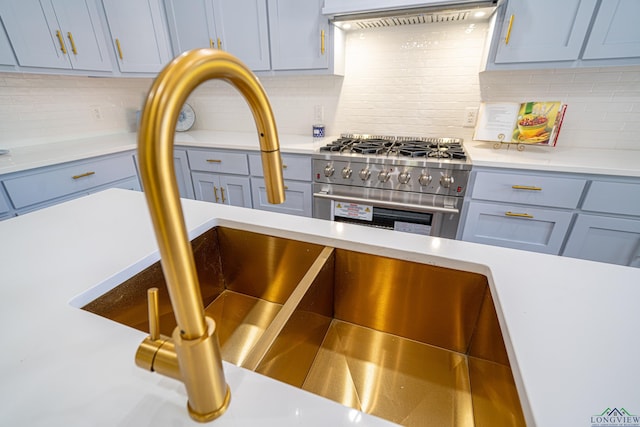 35 Covington Dr, Longview, TX 75602 - kitchen view of stainless steel stove, wall chimney exhaust hood, light countertops, tasteful backsplash, and gray cabinets