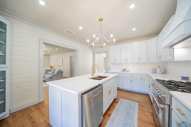 kitchen featuring appliances with stainless steel finishes, sink, a center island with sink, decorative light fixtures, and white cabinetry