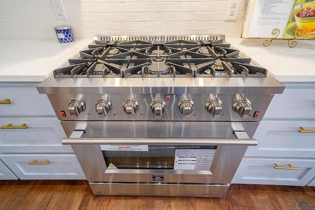 details with dark hardwood / wood-style floors and high end stainless steel range