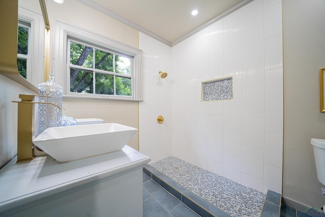 bathroom featuring sink, tile patterned flooring, crown molding, toilet, and tiled shower