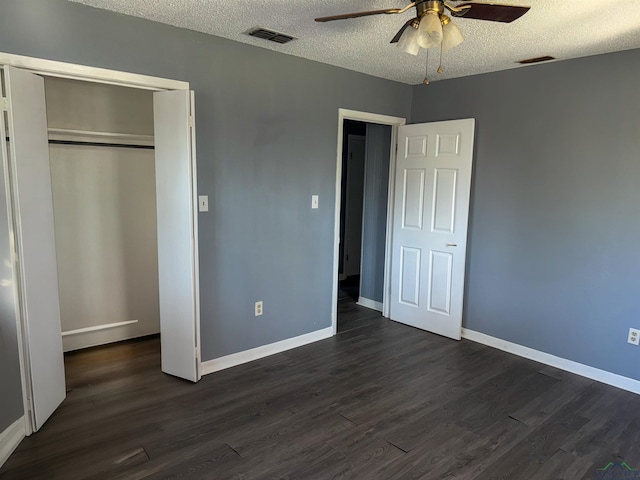 unfurnished bedroom featuring dark wood-style floors, visible vents, a textured ceiling, and baseboards