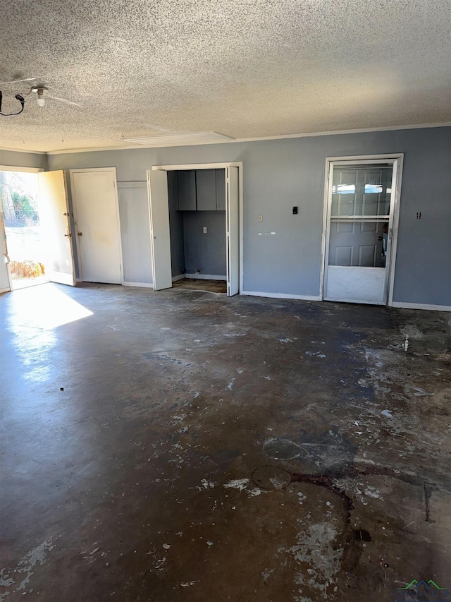 interior space with a textured ceiling, concrete floors, and baseboards