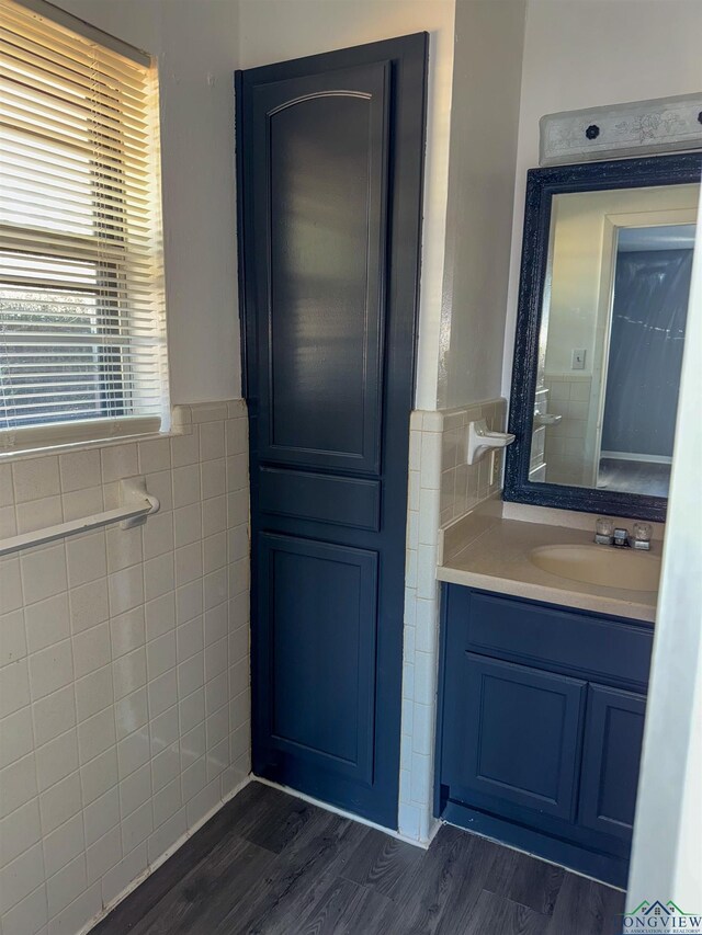 bathroom featuring wainscoting, tile walls, vanity, and wood finished floors