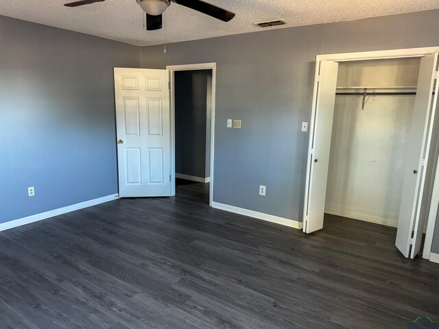 unfurnished bedroom with visible vents, dark wood-type flooring, baseboards, a closet, and a textured ceiling