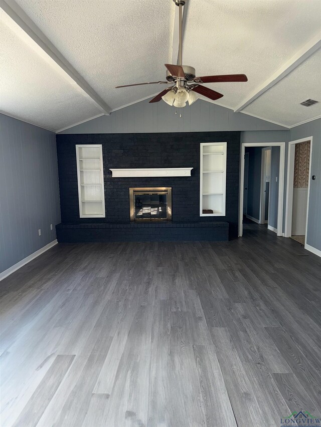 unfurnished living room with a textured ceiling, lofted ceiling with beams, and wood finished floors