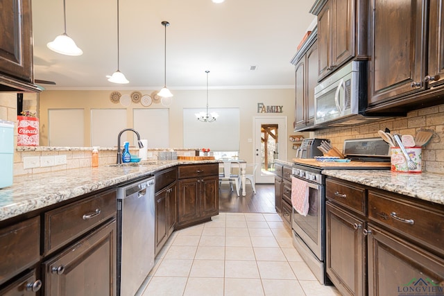 kitchen with appliances with stainless steel finishes, dark brown cabinets, hanging light fixtures, and crown molding