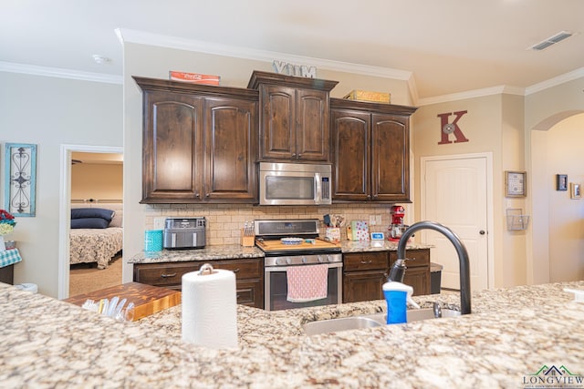 kitchen with sink, stainless steel appliances, dark brown cabinets, and ornamental molding