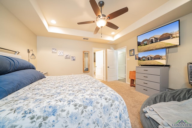 carpeted bedroom with ceiling fan and a raised ceiling