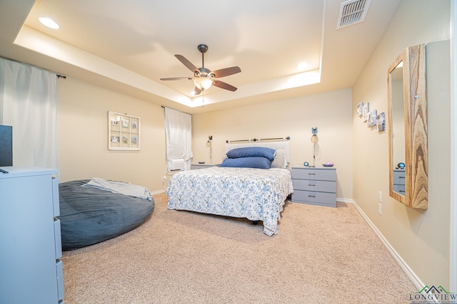 carpeted bedroom featuring ceiling fan and a raised ceiling