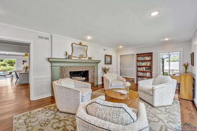 living room with a fireplace, plenty of natural light, visible vents, and crown molding