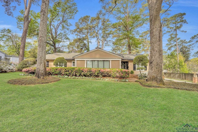 ranch-style home with a front lawn, stucco siding, and fence