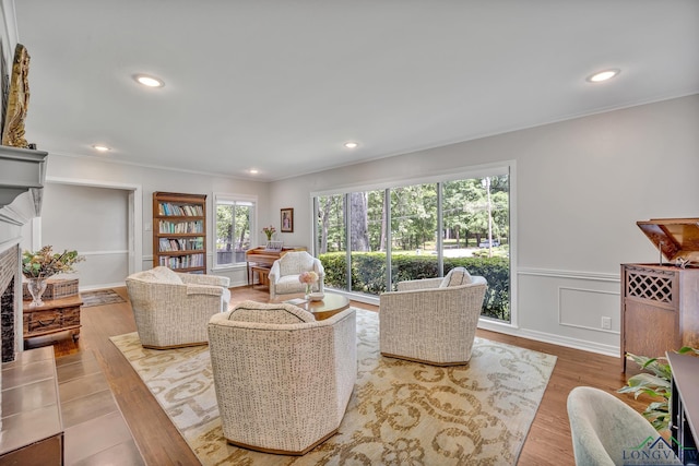 living area featuring recessed lighting, wood finished floors, a fireplace, and ornamental molding