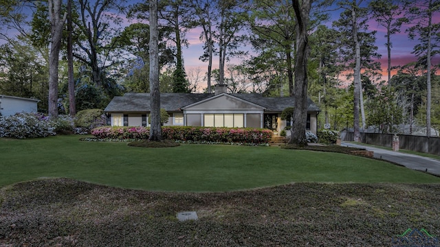 ranch-style house with fence and a front lawn