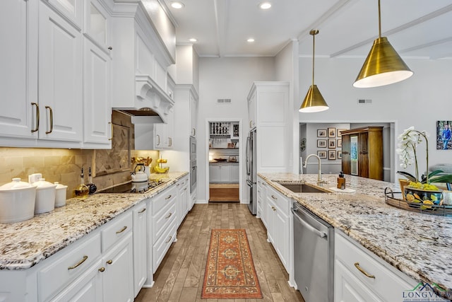 kitchen featuring white cabinets, decorative backsplash, stainless steel appliances, and a sink