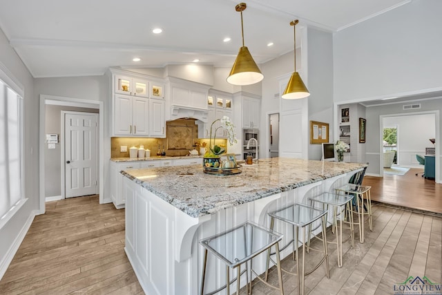 kitchen featuring decorative backsplash, visible vents, light wood-style floors, and white cabinetry