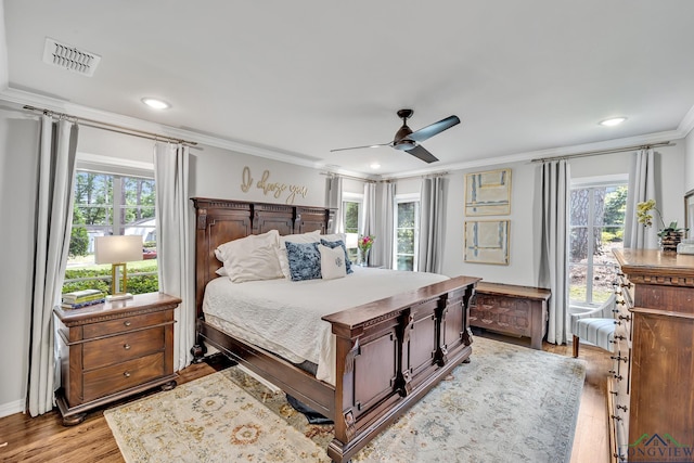 bedroom with multiple windows, ornamental molding, light wood-style floors, and visible vents