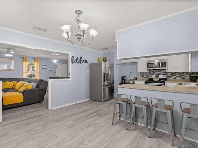 kitchen with white cabinetry, hanging light fixtures, stainless steel appliances, kitchen peninsula, and a breakfast bar