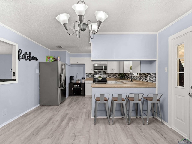 kitchen featuring kitchen peninsula, appliances with stainless steel finishes, backsplash, decorative light fixtures, and white cabinets