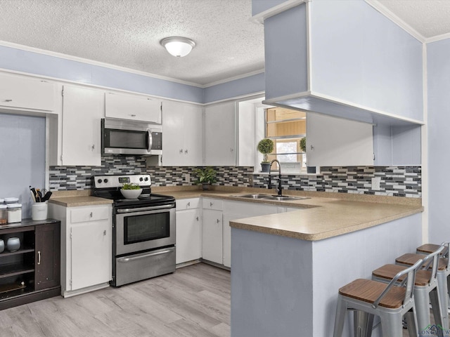 kitchen with kitchen peninsula, sink, white cabinetry, and stainless steel appliances