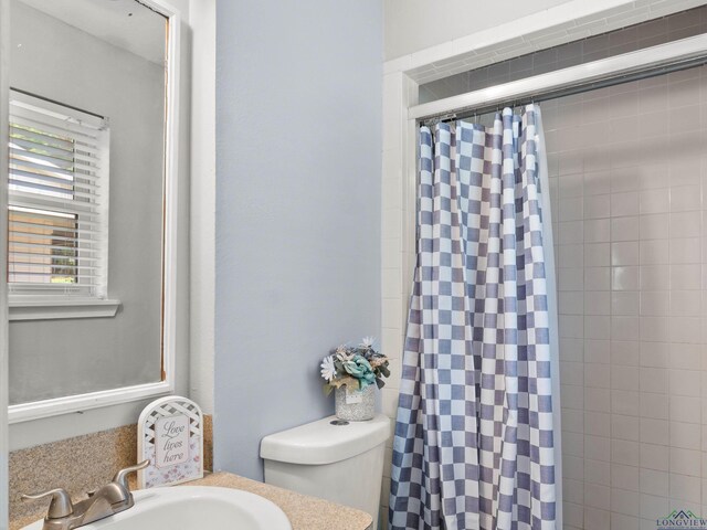 bathroom featuring curtained shower, vanity, and toilet