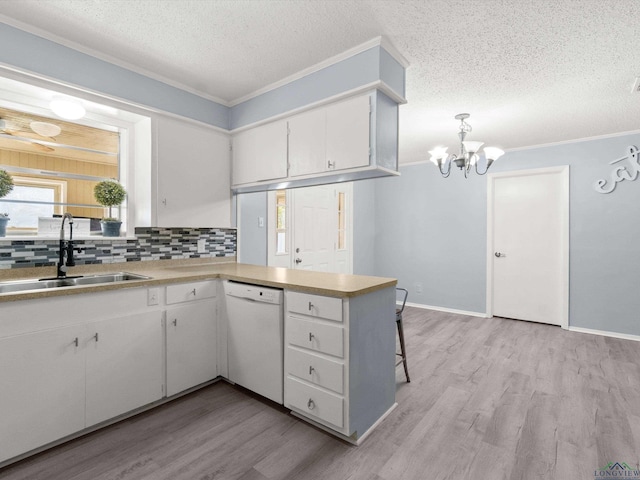 kitchen with sink, hanging light fixtures, kitchen peninsula, white dishwasher, and white cabinets