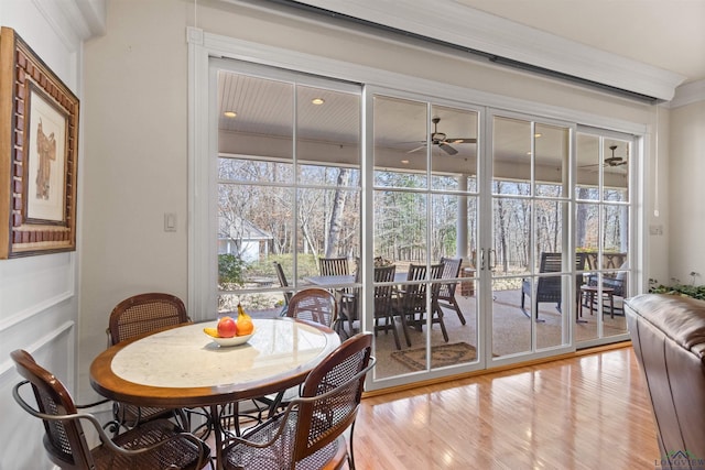 dining space with a wealth of natural light, wood-type flooring, ornamental molding, and ceiling fan