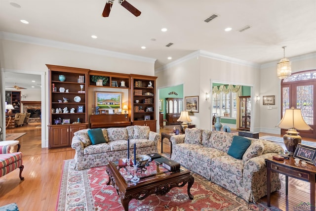 living room with ornamental molding, light hardwood / wood-style floors, and ceiling fan