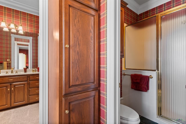 bathroom with ornamental molding, vanity, toilet, and a shower with door