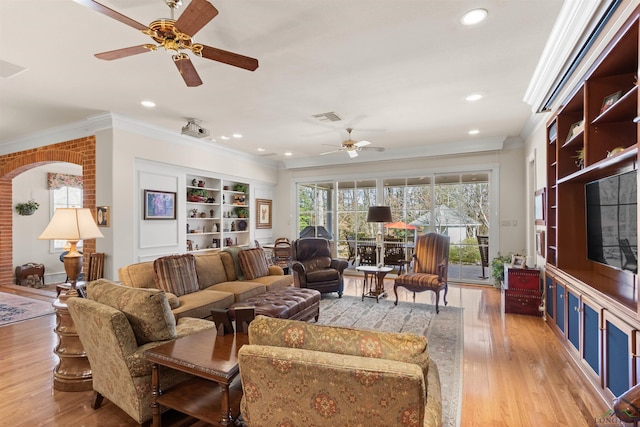 living room with ceiling fan, crown molding, light hardwood / wood-style flooring, and built in shelves