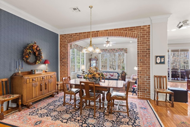 dining area with crown molding, hardwood / wood-style flooring, and ceiling fan with notable chandelier