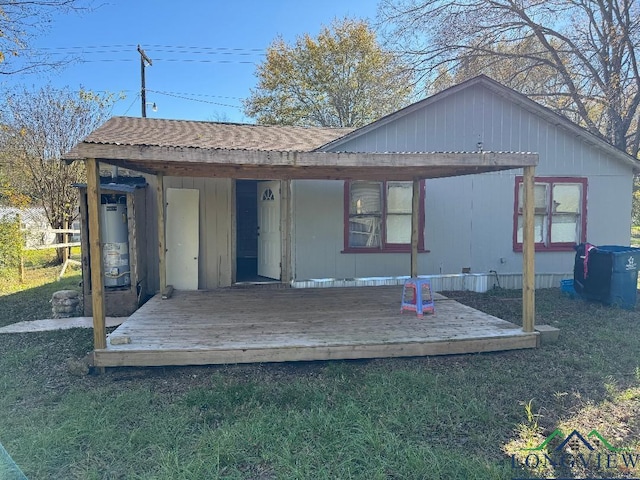 back of property with a lawn, gas water heater, and a wooden deck