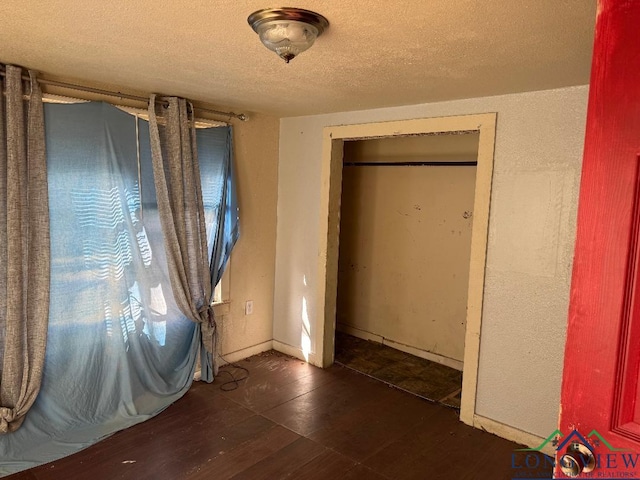 unfurnished bedroom featuring dark hardwood / wood-style flooring, a textured ceiling, and a closet