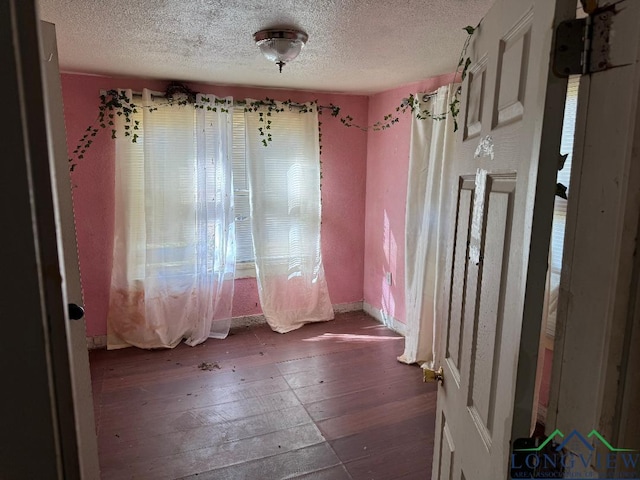 unfurnished room featuring a textured ceiling and dark wood-type flooring