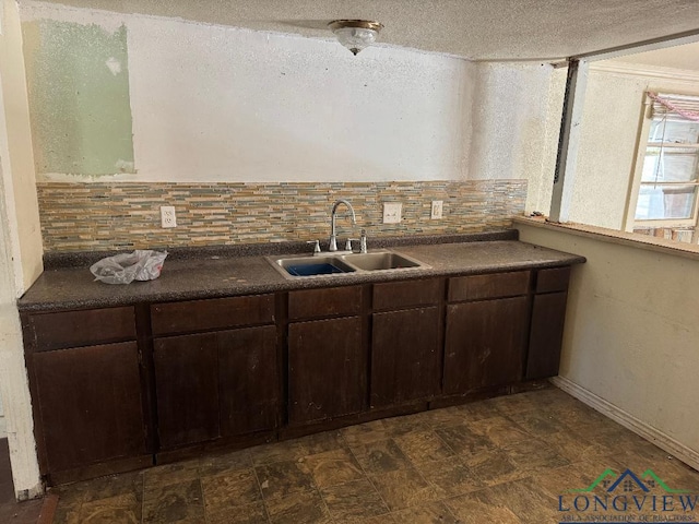 kitchen with decorative backsplash, dark brown cabinetry, and sink