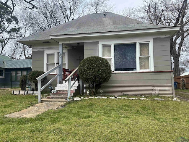 bungalow-style house featuring a shingled roof and a front lawn