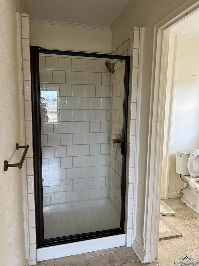 bathroom featuring crown molding, toilet, and a shower with door