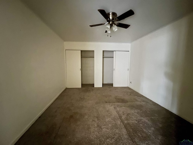 unfurnished bedroom featuring two closets, carpet floors, and ceiling fan