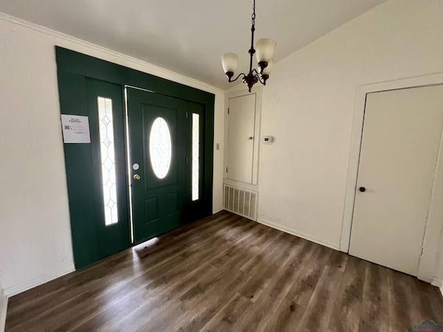 entryway with crown molding, dark wood-type flooring, and a chandelier