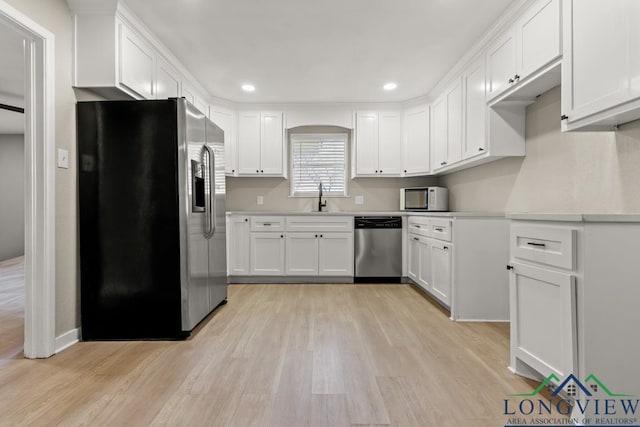 kitchen featuring sink, appliances with stainless steel finishes, white cabinets, and light hardwood / wood-style flooring