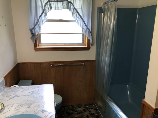 full bathroom featuring wooden walls, toilet, vanity, and washtub / shower combination