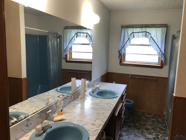 bathroom with wooden walls, plenty of natural light, vanity, and a textured ceiling