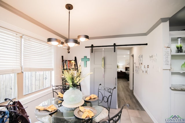 dining space with a barn door, ornamental molding, and baseboards